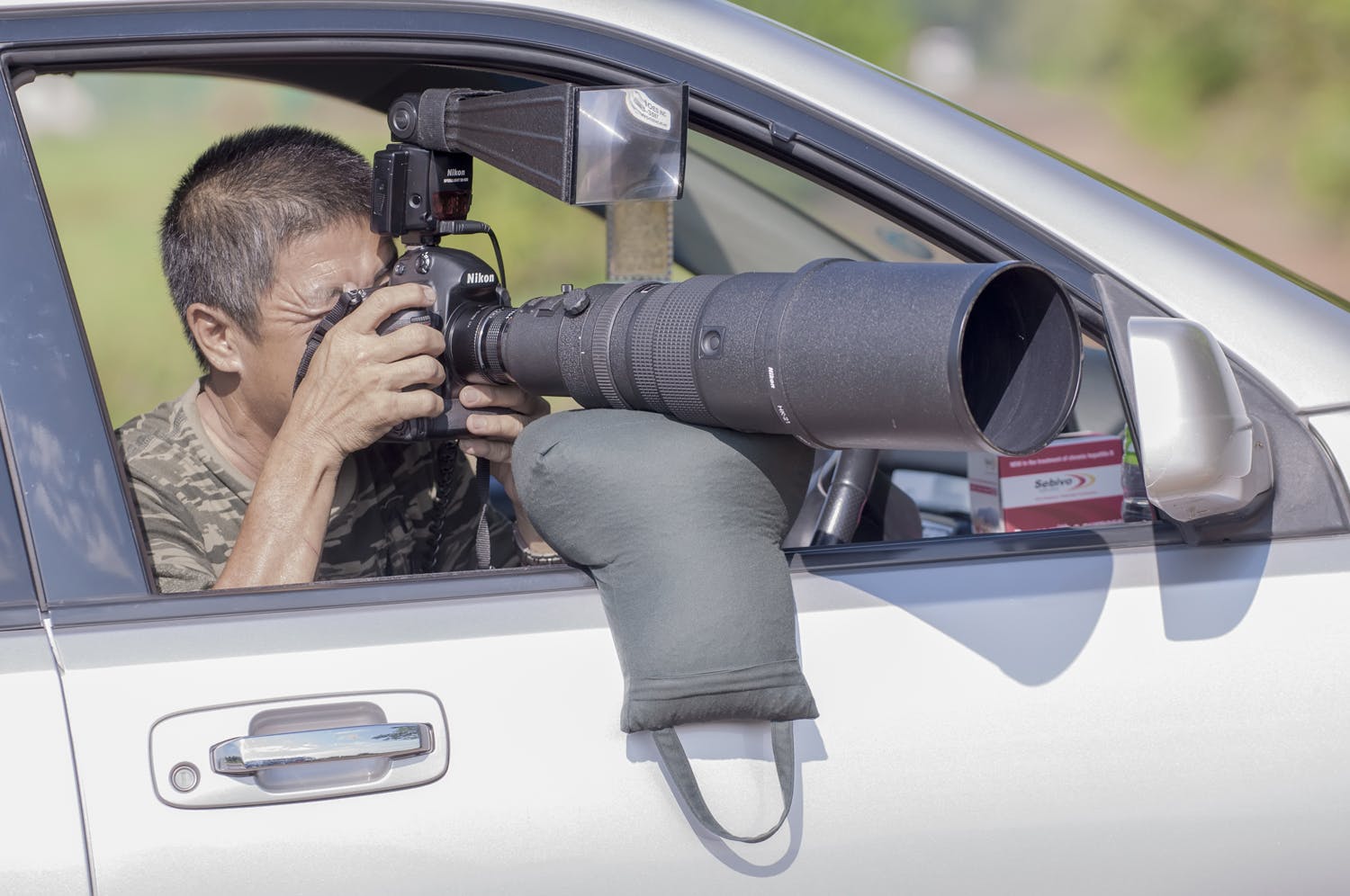 Fotograf i bil använder ärtpåse för att stabilisera zoomobjektiv.